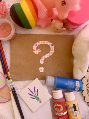 A question mark on a brown envelope surrounded by colorful items.